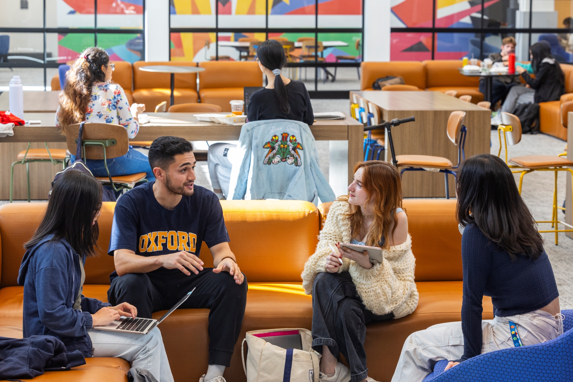 four students talking in a circle sitting on couches in the student center